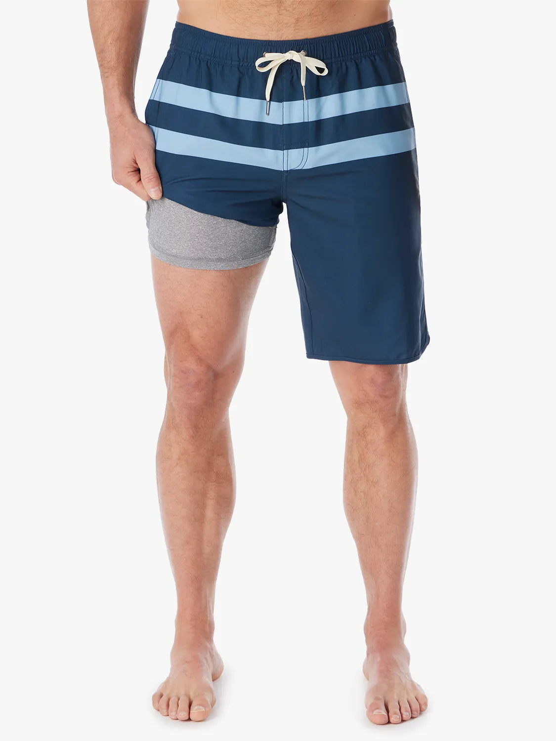 A person wearing a pair of 10 inch navy anchor trunk shorts with two light blue horizontal stripes and a drawstring waist, showing the liner with a white background.
