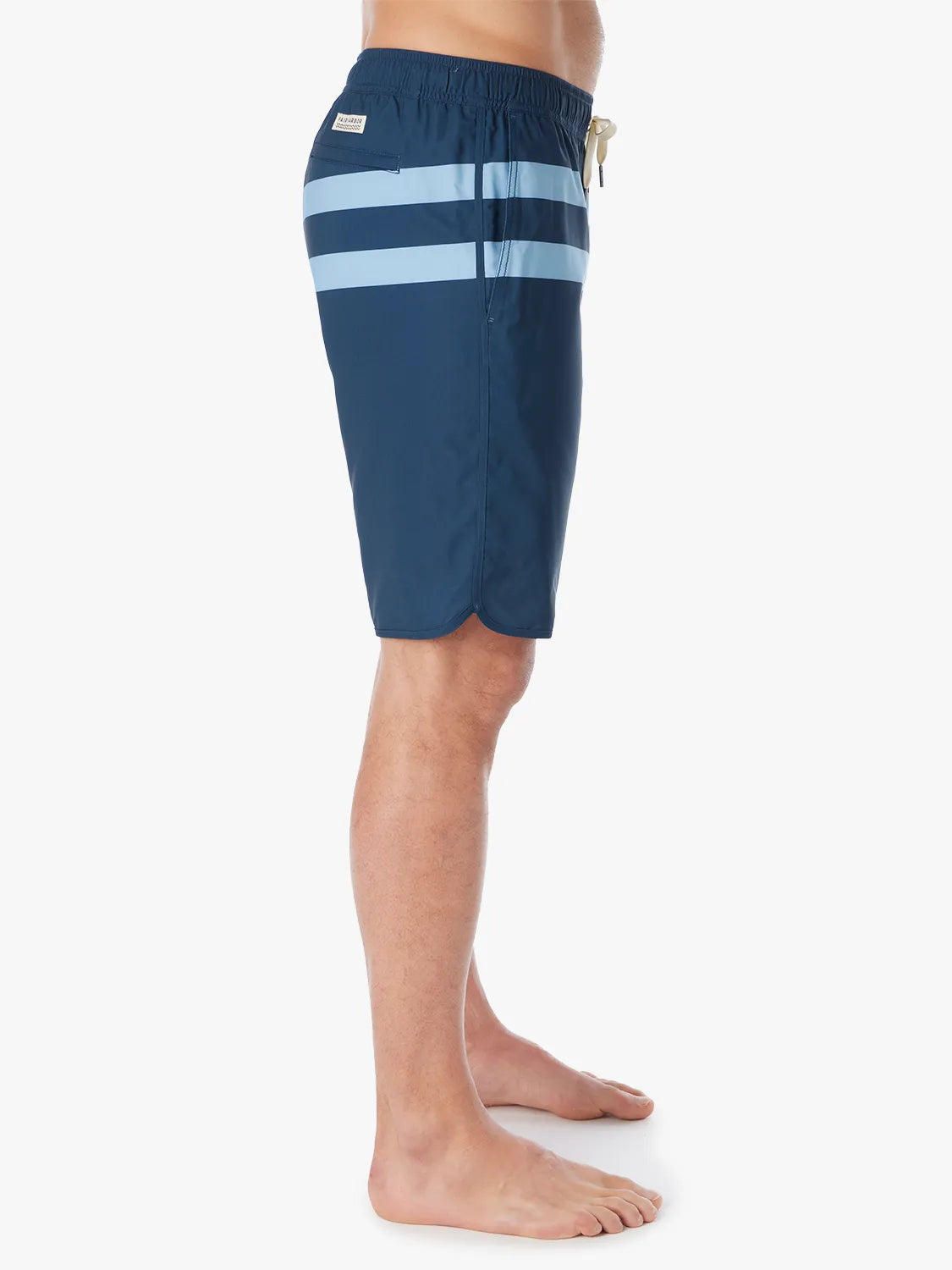 A person wearing a pair of 10 inch navy anchor trunk shorts with two light blue horizontal stripes and a drawstring waist, showing the side view with a white background.