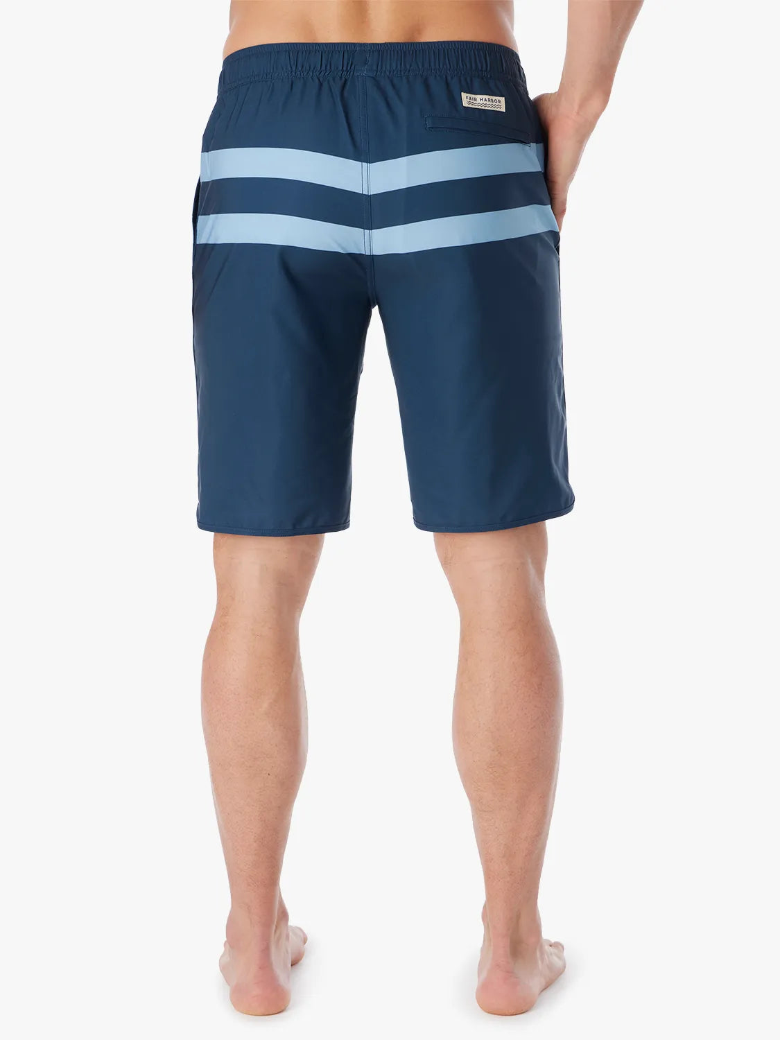 A person wearing a pair of 10 inch navy anchor trunk shorts with two light blue horizontal stripes and a drawstring waist, showing the back view with a white background.