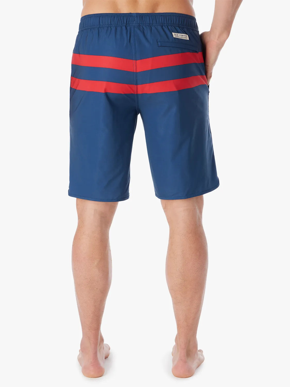 A person wearing a pair of 10 inch navy anchor trunk shorts with two red horizontal stripes, showing the back view with a white background.