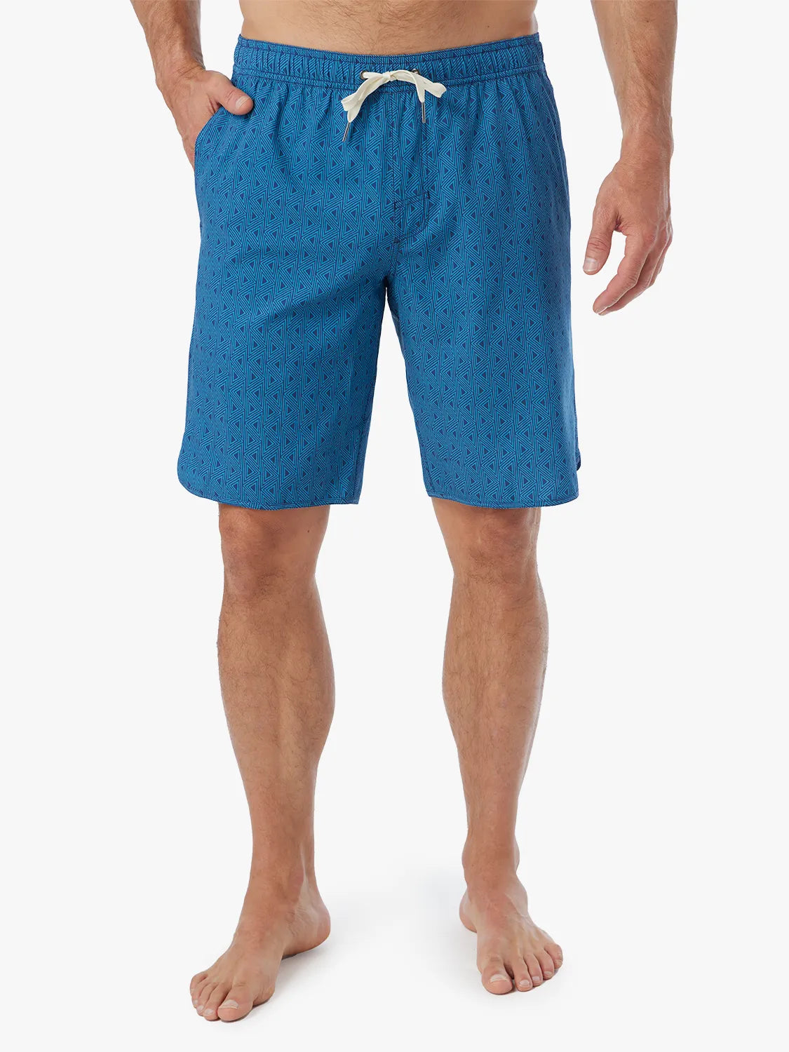 Person wearing electric blue geometric patterned Anchor Trunk in 10 inch inseam with a drawstring waistband and hand in side pocket.