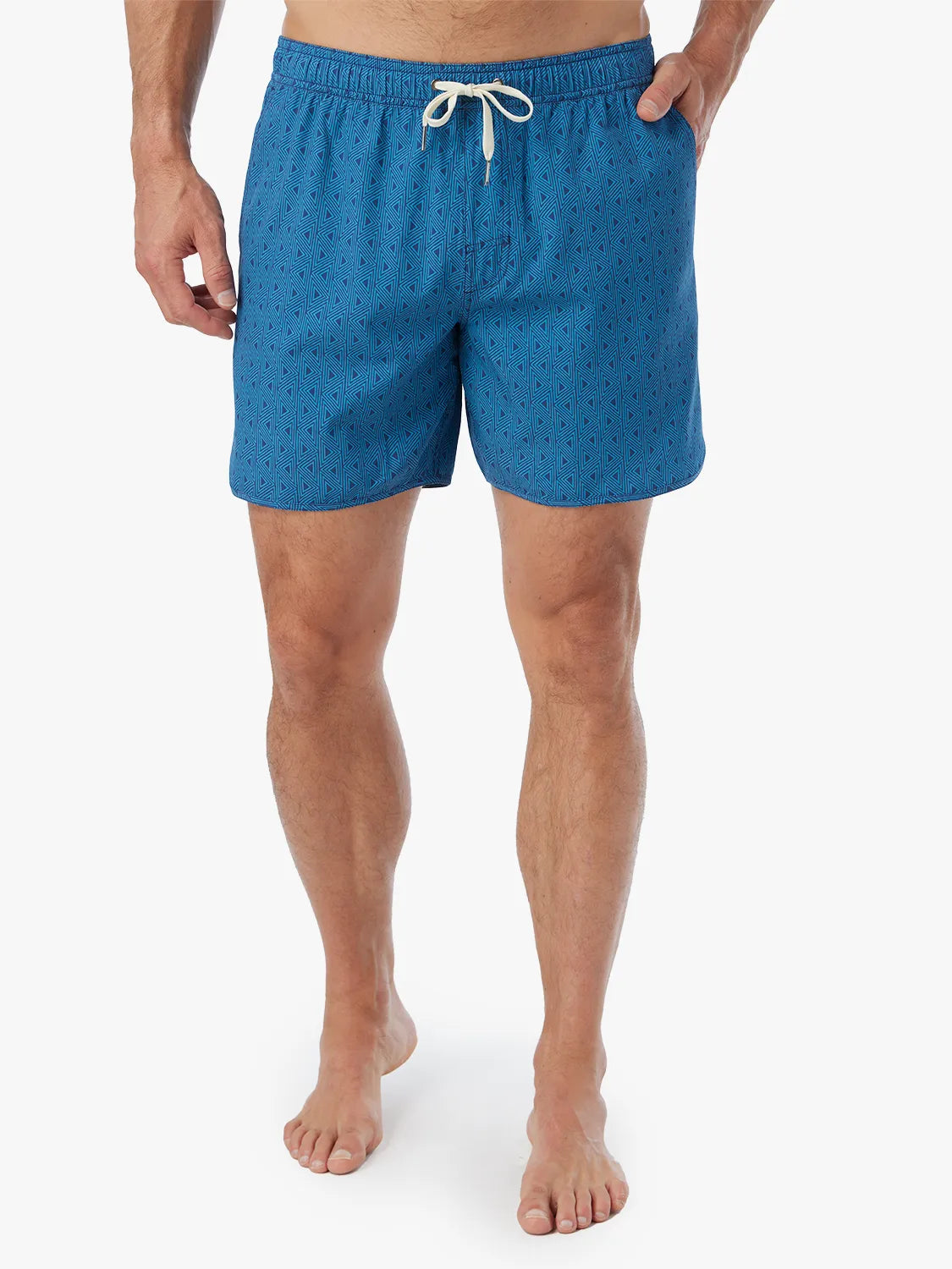 Person wearing electric blue geometric patterned Anchor Trunk in 6 inch inseam with a drawstring waistband and hand in side pocket.