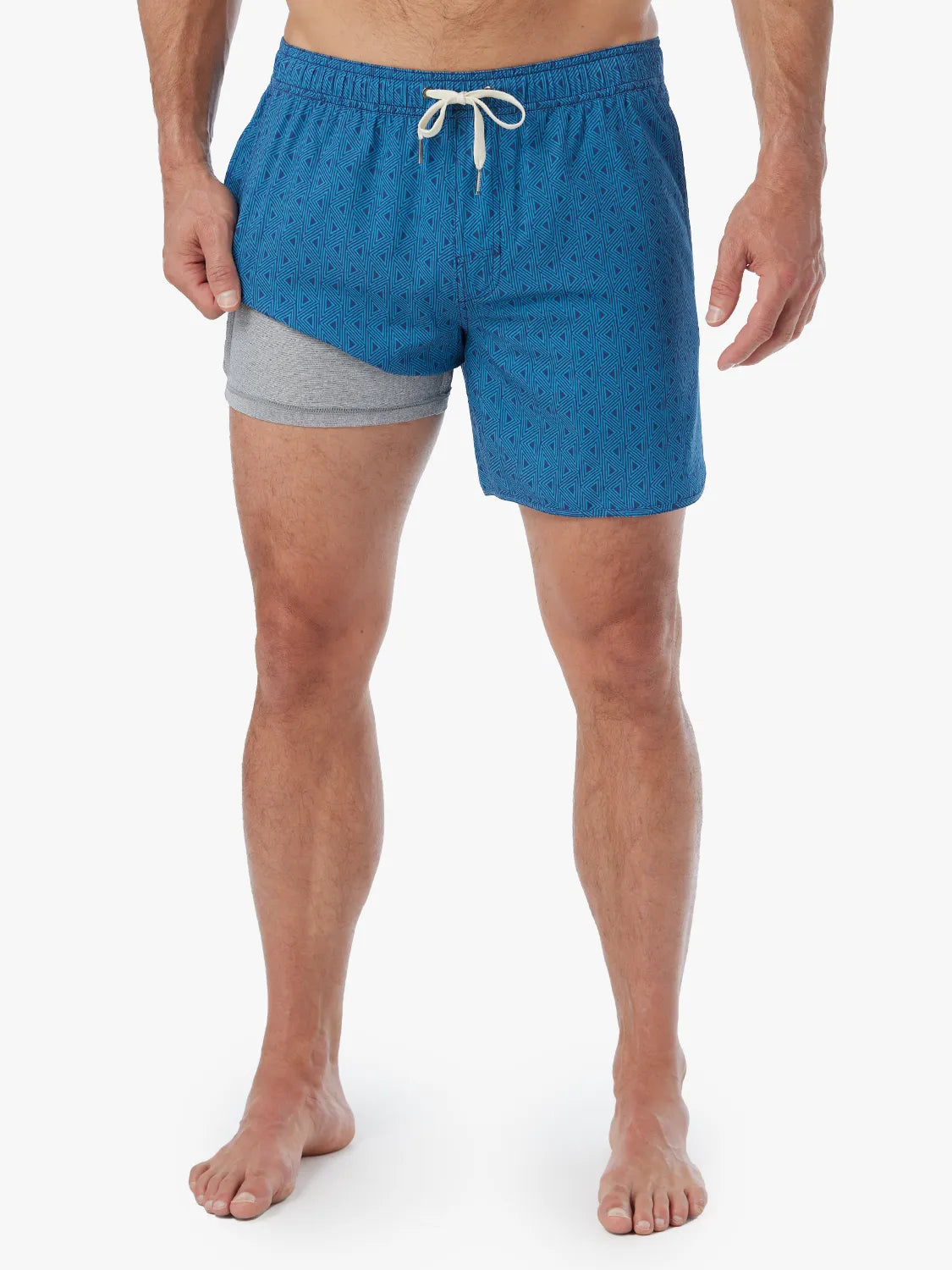Person wearing electric blue geometric patterned Anchor Trunk in 6 inch inseam with a drawstring waistband and showing the liner.