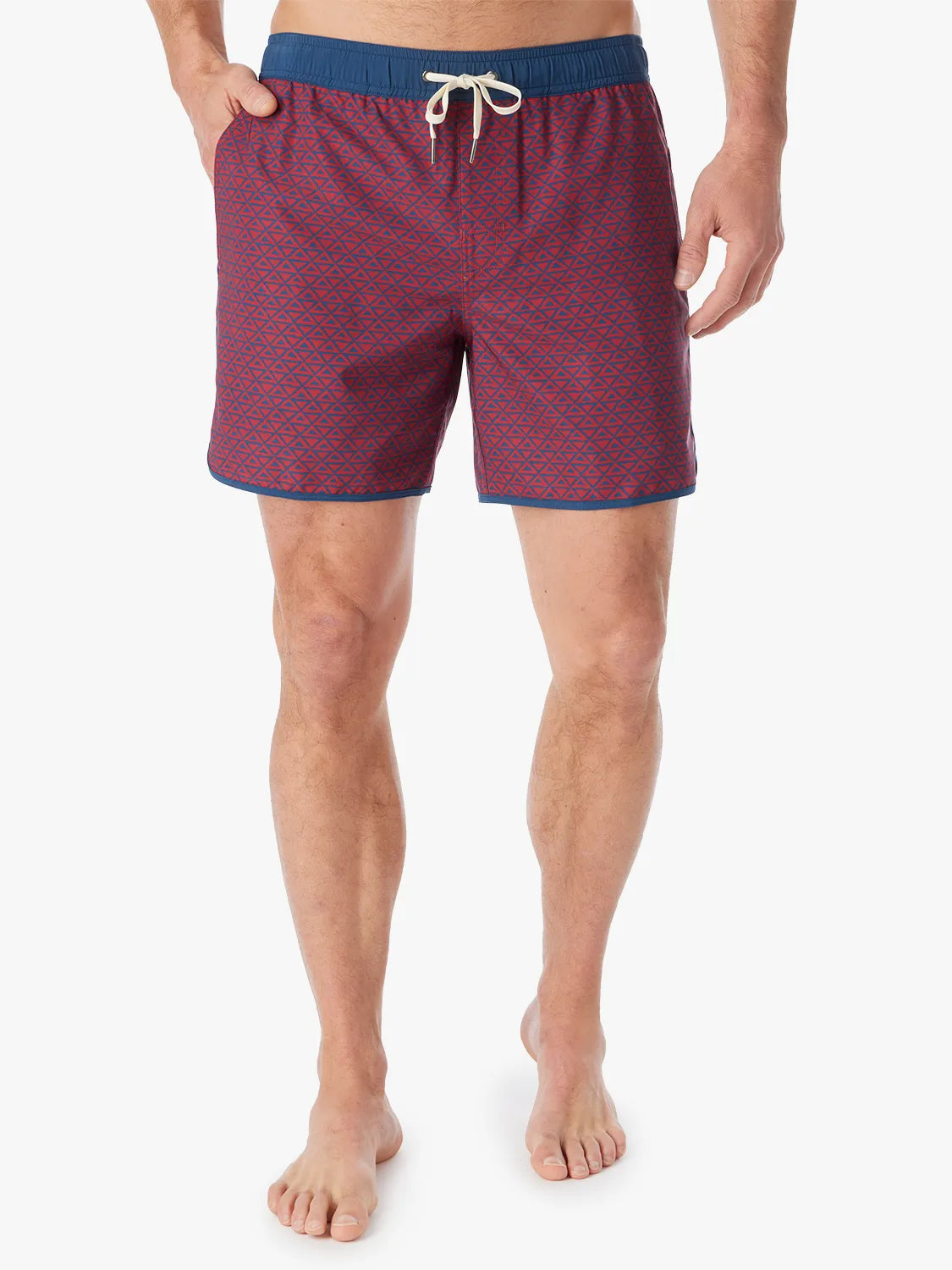 Person wearing a pair of Anchor Trunks with a nautical red wavy geo pattern in 6 Inch inseam. Featuring a drawstring waist and a hand in left side pocket, with a white background.