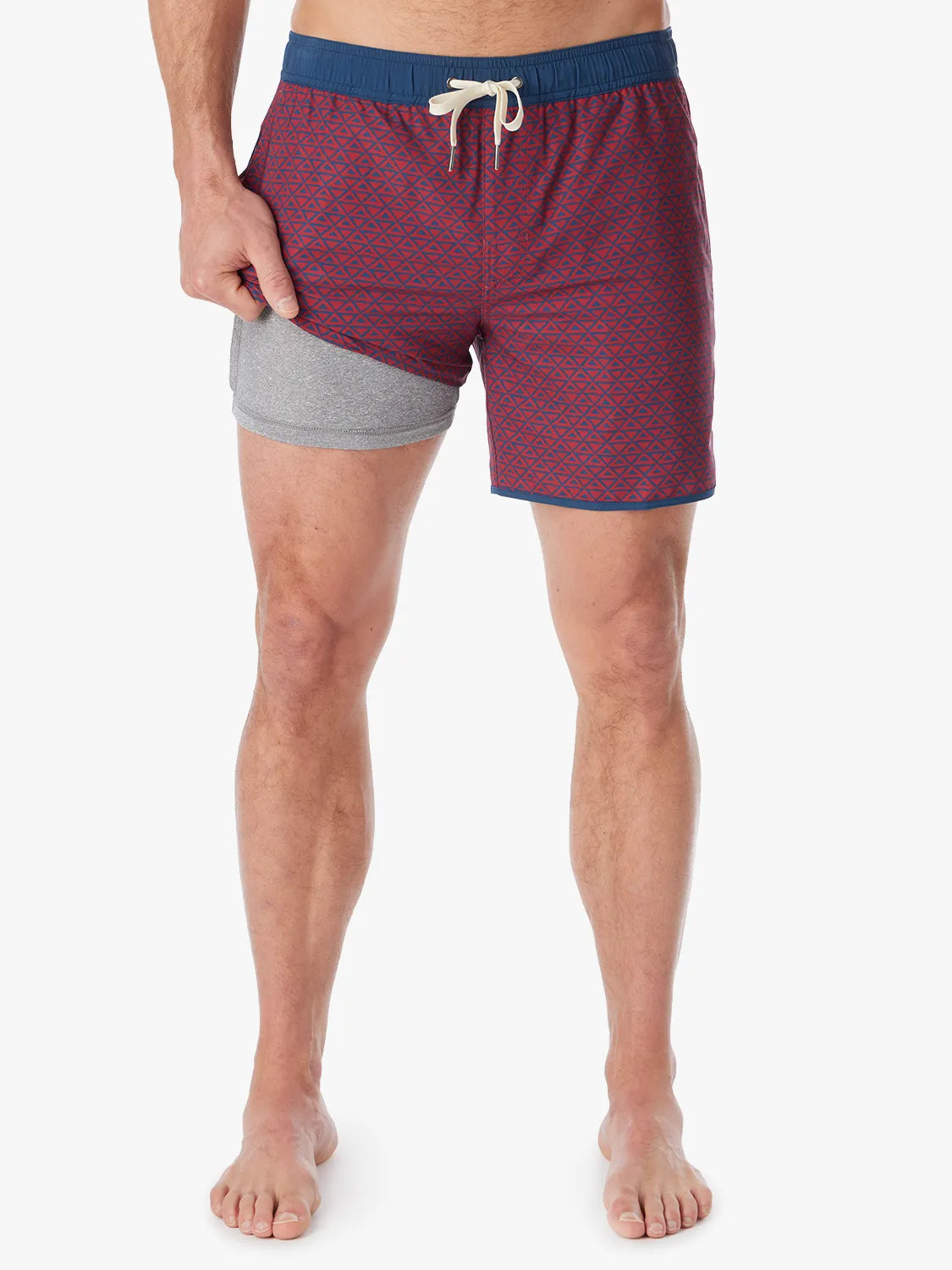 Person wearing a pair of Anchor Trunks with a nautical red wavy geo pattern in 6 Inch inseam. Featuring a drawstring waist and showing the liner, with a white background.