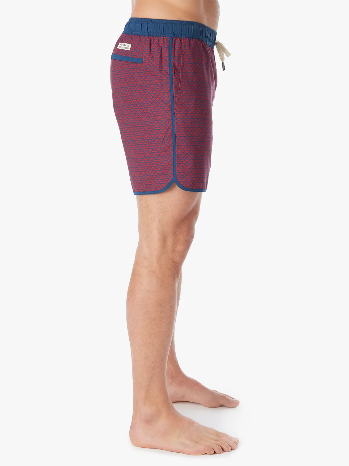 Person wearing a pair of Anchor Trunks with a nautical red wavy geo pattern in 6 Inch inseam. Featuring a drawstring waist and side view of trunk, with a white background.