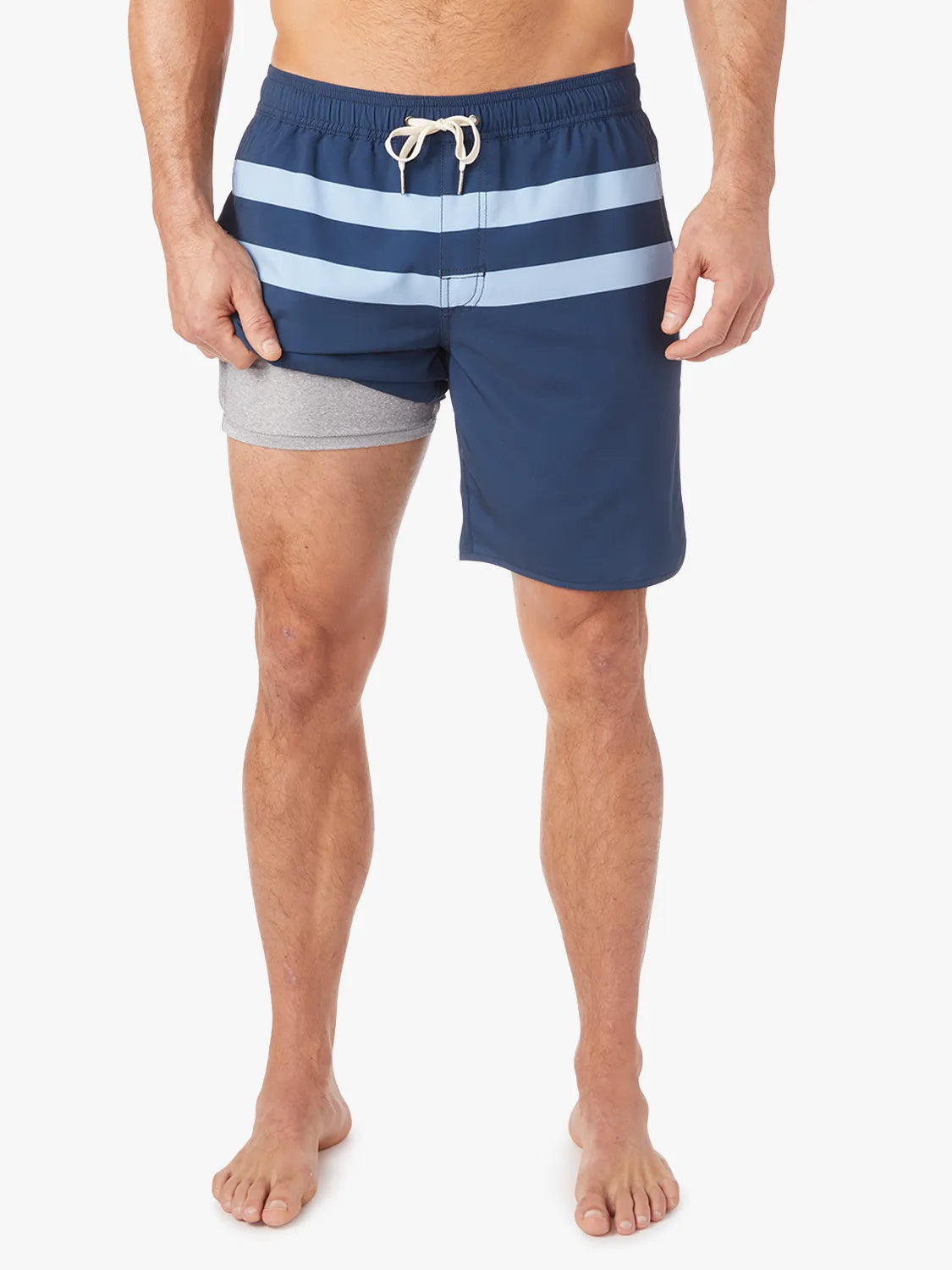 A person wearing a pair of 8 inch navy anchor trunk shorts with two light blue horizontal stripes and a drawstring waist, showing the liner with a white background.