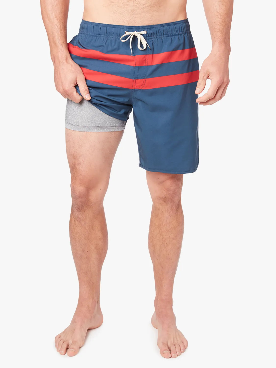 A person wearing a pair of 8 inch navy anchor trunk shorts with two red horizontal stripes and a drawstring waist, showing the liner with a white background.