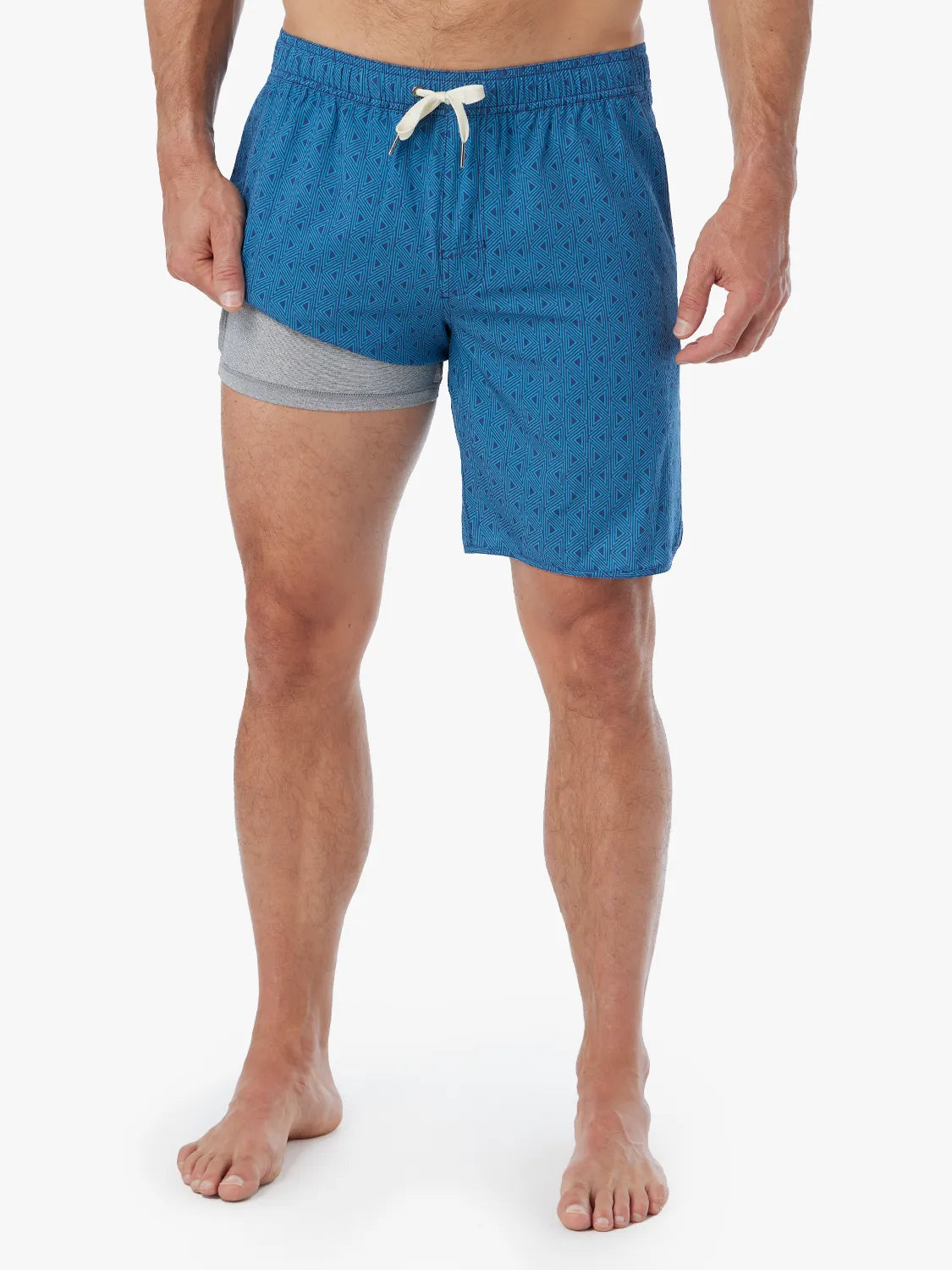 Person wearing electric blue geometric patterned Anchor Trunk in 8 inch inseam with a drawstring waistband and showing the liner.