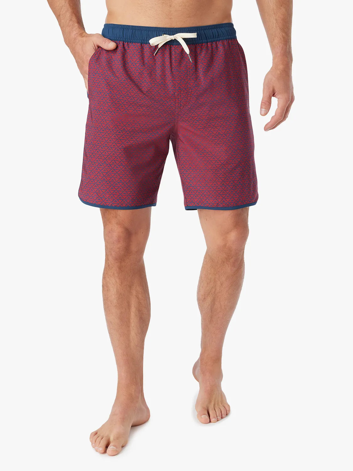Person wearing a pair of Anchor Trunks with a nautical red wavy geo pattern in 8 Inch inseam. Featuring a drawstring waist and a hand in left side pocket, with a white background.