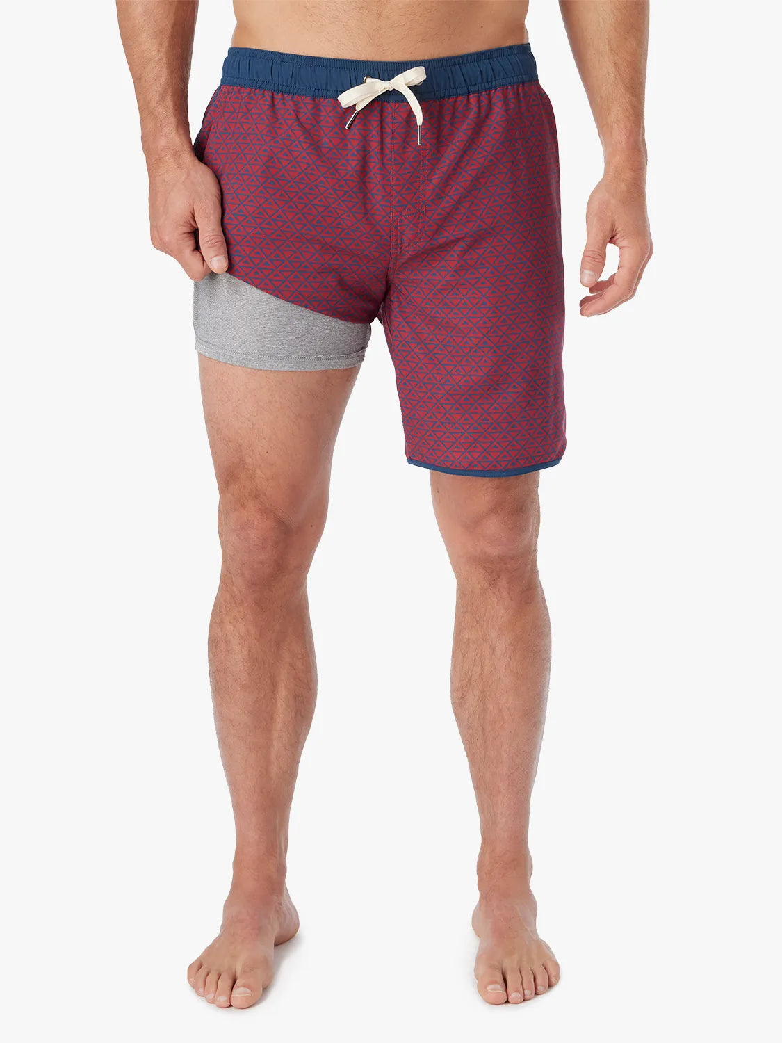 Person wearing a pair of Anchor Trunks with a nautical red wavy geo pattern in 8 Inch inseam. Featuring a drawstring waist and showing the liner, with a white background.