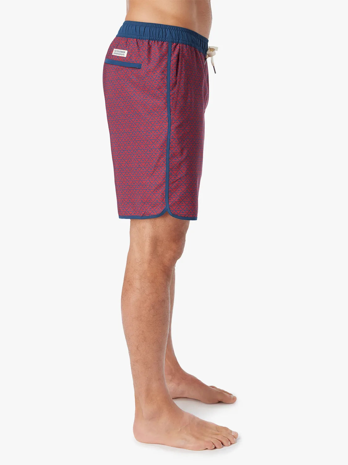 Person wearing a pair of Anchor Trunks with a nautical red wavy geo pattern in 8 Inch inseam. Featuring a drawstring waist and side view of trunk, with a white background.