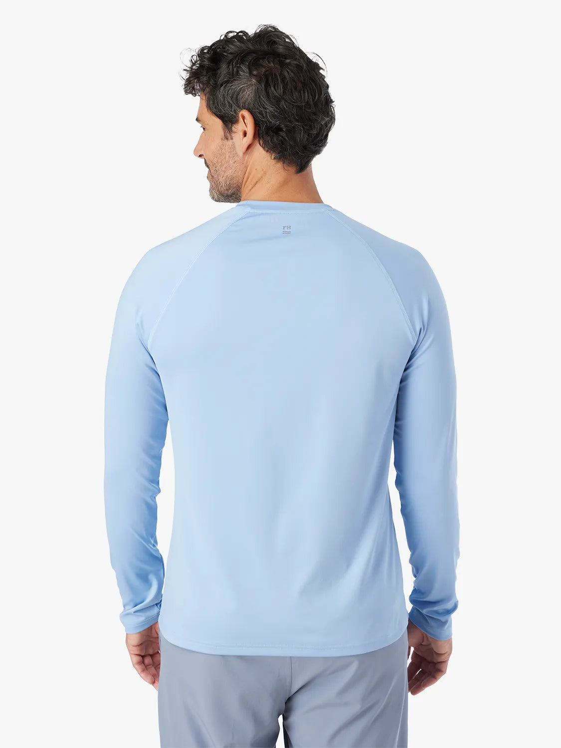 A person wearing the long-sleeved light blue Anchor Rashguard with a crewneck design, showing back view.