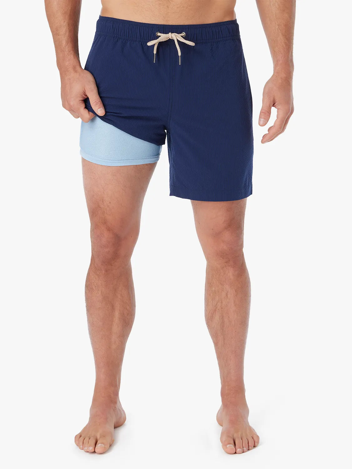 Person wearing a pair Bayberry swim trunks in Navy blue seersucker with a drawstring waistband, showing the lining.