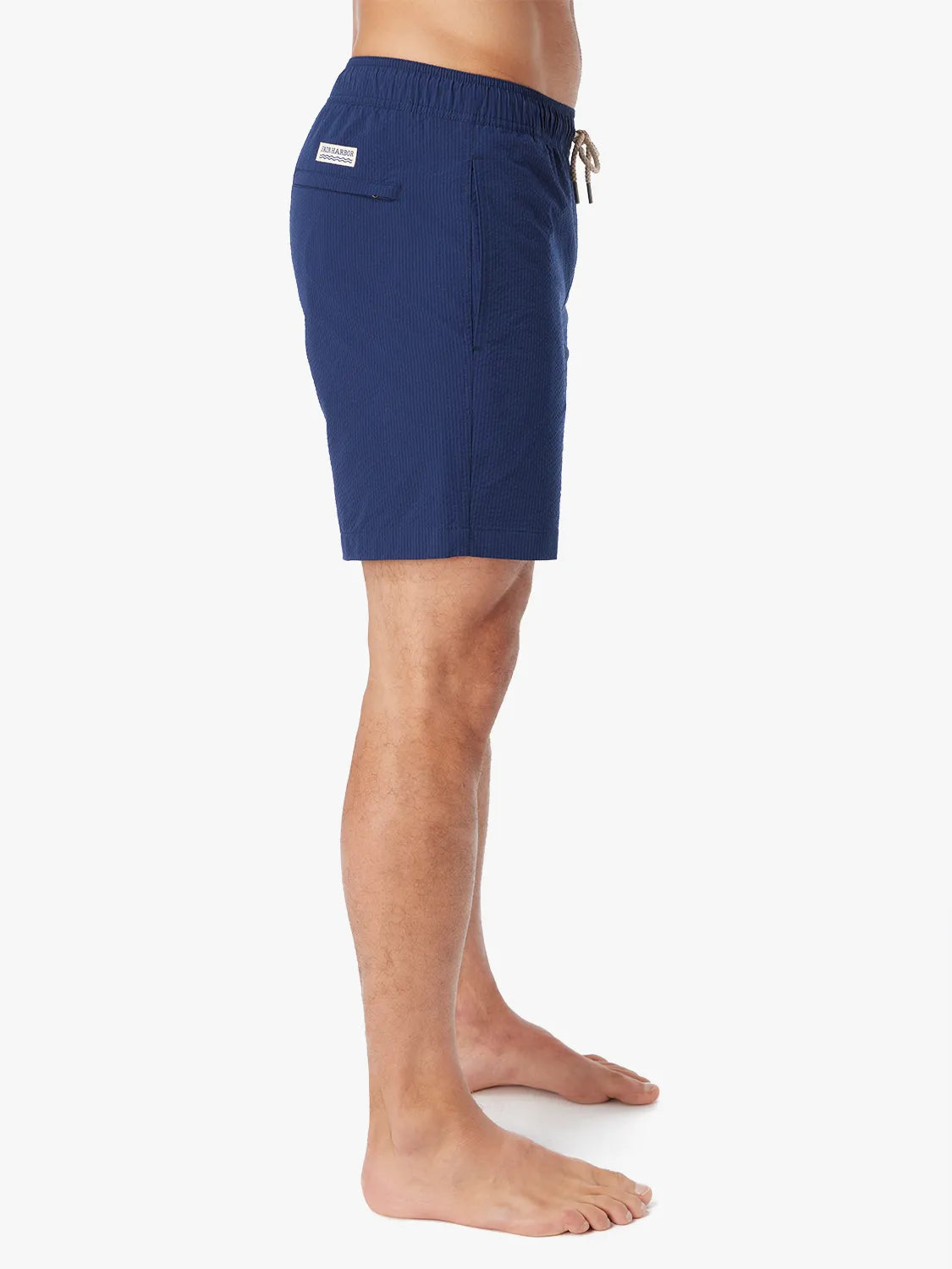 Person wearing a pair Bayberry swim trunks in Navy blue seersucker with a drawstring waistband and side view of shorts.