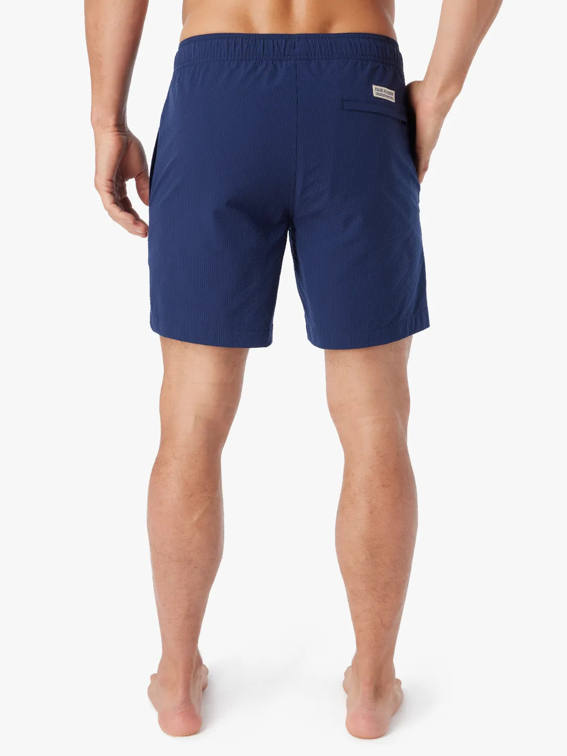 Person wearing a pair Bayberry swim trunks in Navy blue seersucker showing the back view.