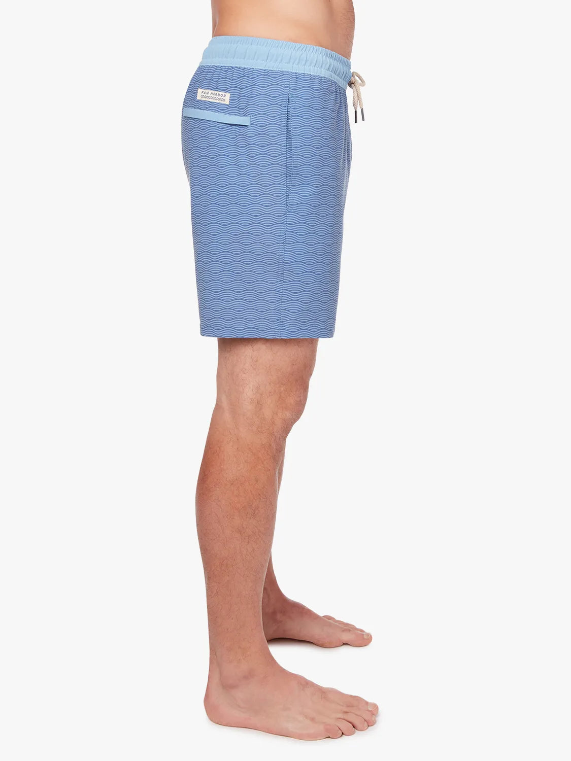 A person wearing a pair of blue waves Bayberry trunks with a drawstring elastic waistband, showing the side view.