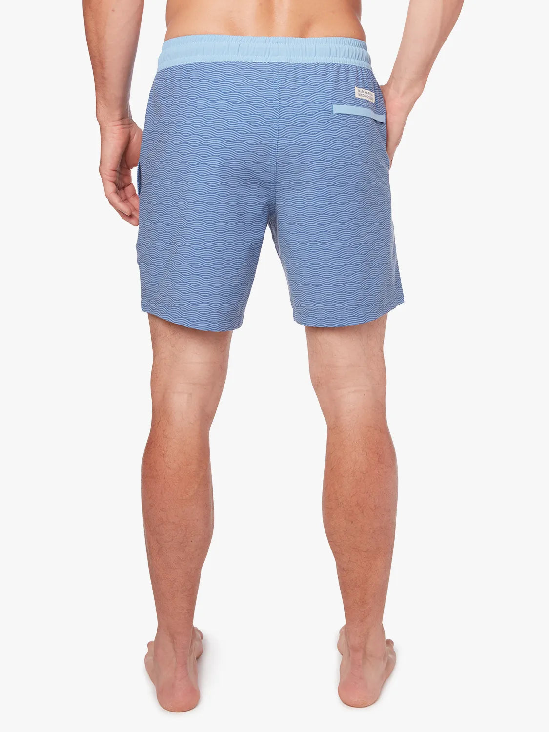 A person wearing a pair of blue waves Bayberry trunks with a drawstring elastic waistband, showing the back view.