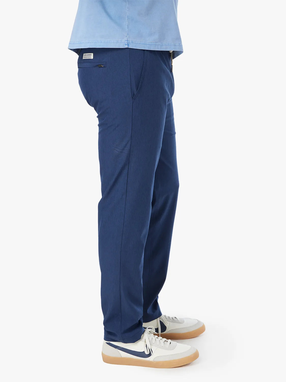 Person wearing a pair of navy blue one pants with a white drawstring on a white background. Paired with tshirt and white sneakers, showing the side view.