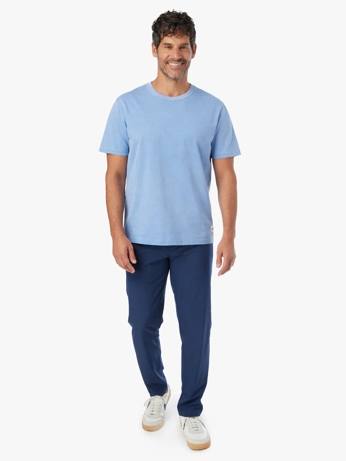 Person wearing a pair of navy blue one pants with a white drawstring on a white background. Paired with tshirt and white sneakers.