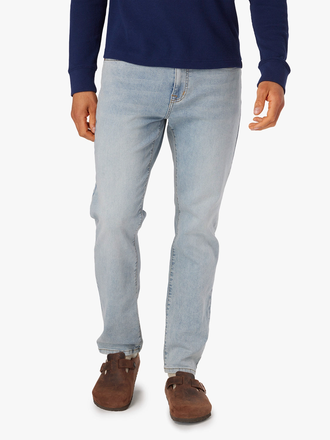 Person wearing light wash driftwood jeans and a navy shirt on a white background