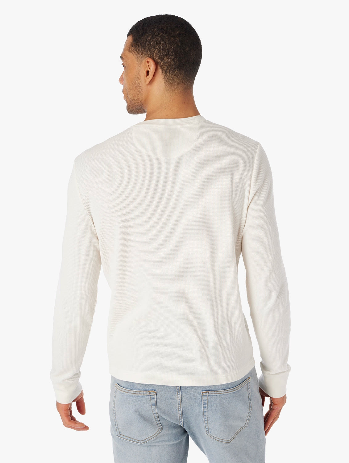 Man wearing beige hudson waffle crewneck long sleeve shirt on a white background, paired with driftwood denim pants. Showing the back view of shirt.