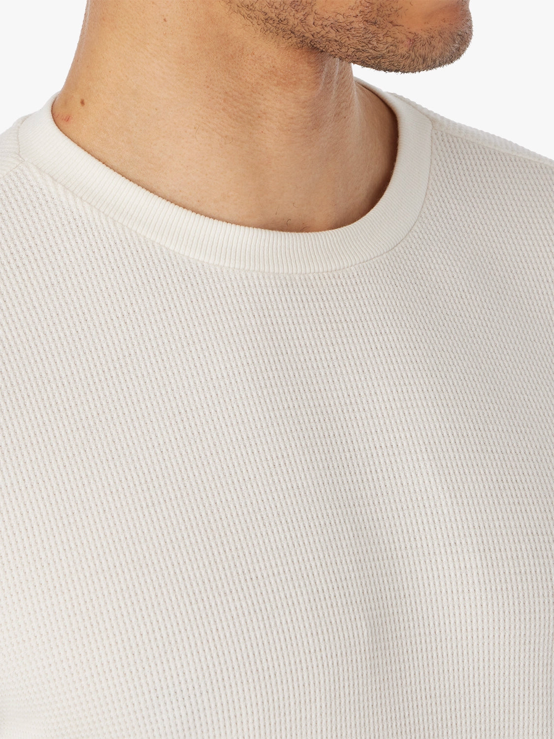 Close-up of a person wearing a beige hudson waffle shirt, showing fabric and neckline detail with a neutral background