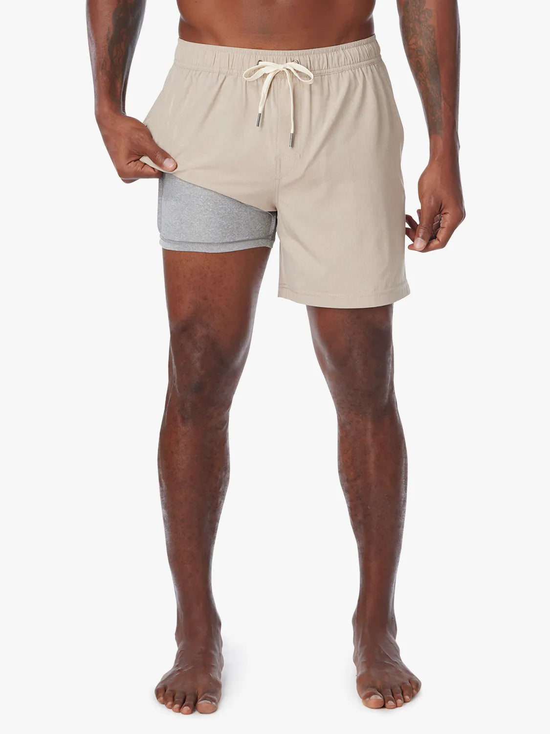 Man wearing a khaki one shorts in 8 inch inseam with a drawstring on a white background, showing the liner underneath.