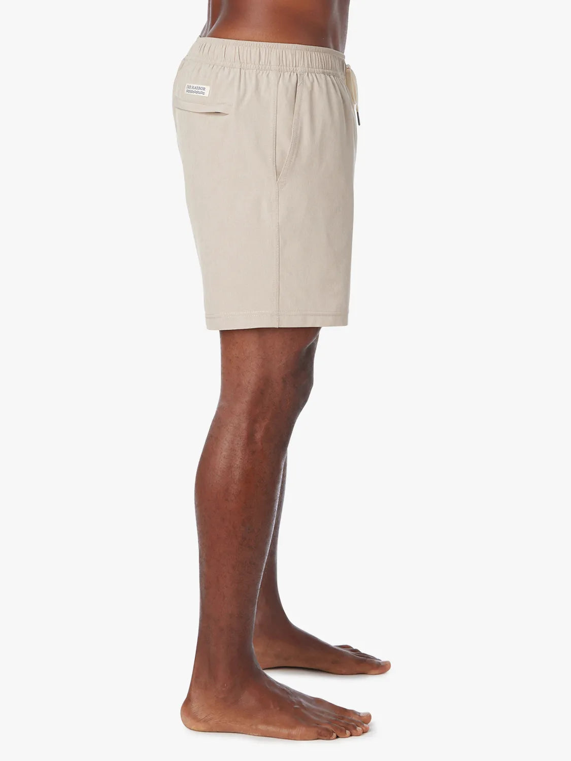 Man wearing a khaki one shorts in 6 inch inseam with a drawstring on a white background, showing the side view.