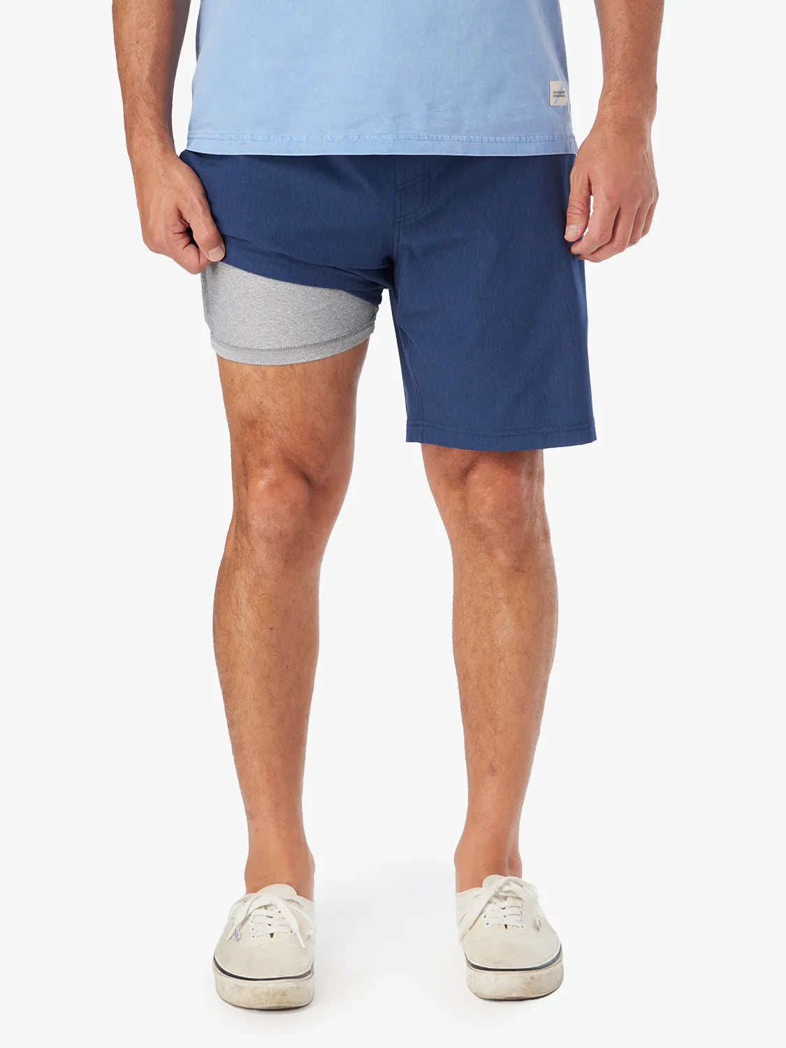 Person wearing a pair of navy 8 inch one shorts with a drawstring on a white background. Showing the liner underneath.