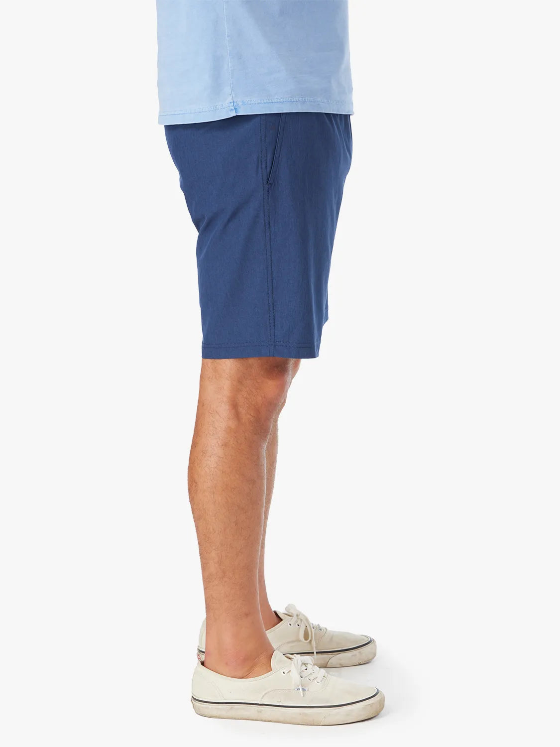 Person wearing a pair of navy 8 inch one shorts with a drawstring on a white background. Showing the side view.