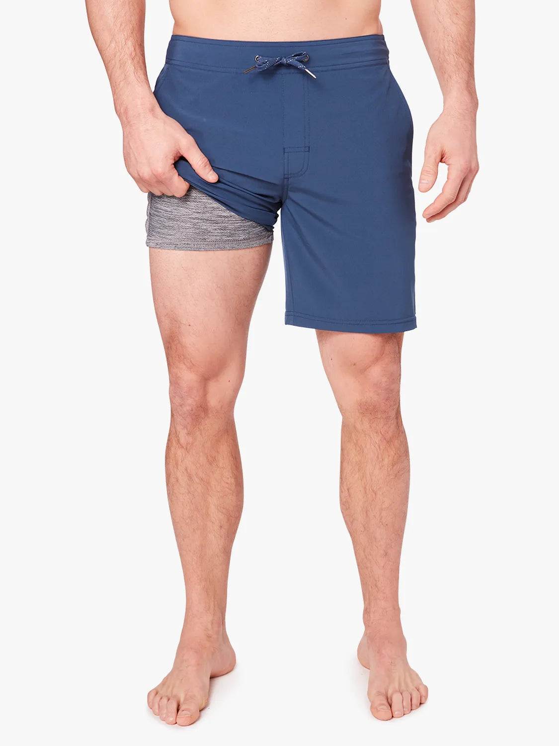 Person wearing a pair navy blue ozone trunks with a drawstring on a white background, showing liner underneath.
