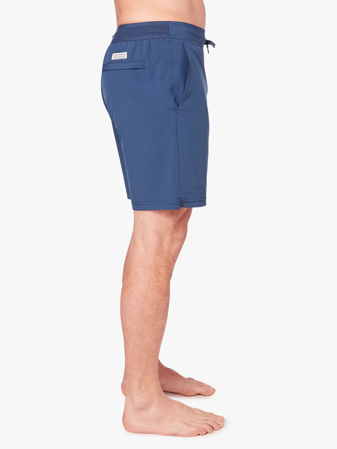 Person wearing a pair navy blue ozone trunks with a drawstring on a white background, showing side view.