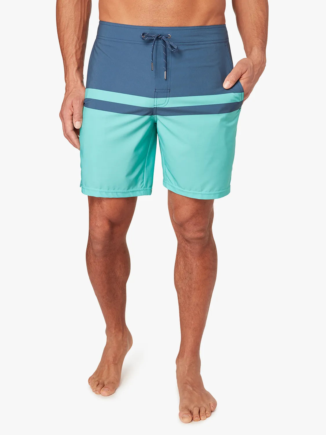 Person wearing a pair of navy blue and teal color blocked ozone board shorts on a white background