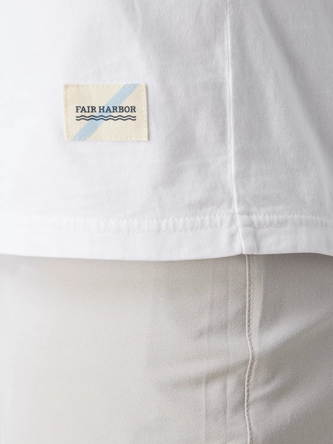 Close up of white saltaire t-shirt fabric and brand logo patch.