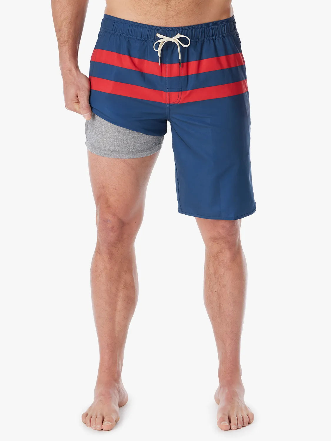 A person wearing a pair of 10 inch navy anchor trunk shorts with two red horizontal stripes and a drawstring waist, showing the liner with a white background. 