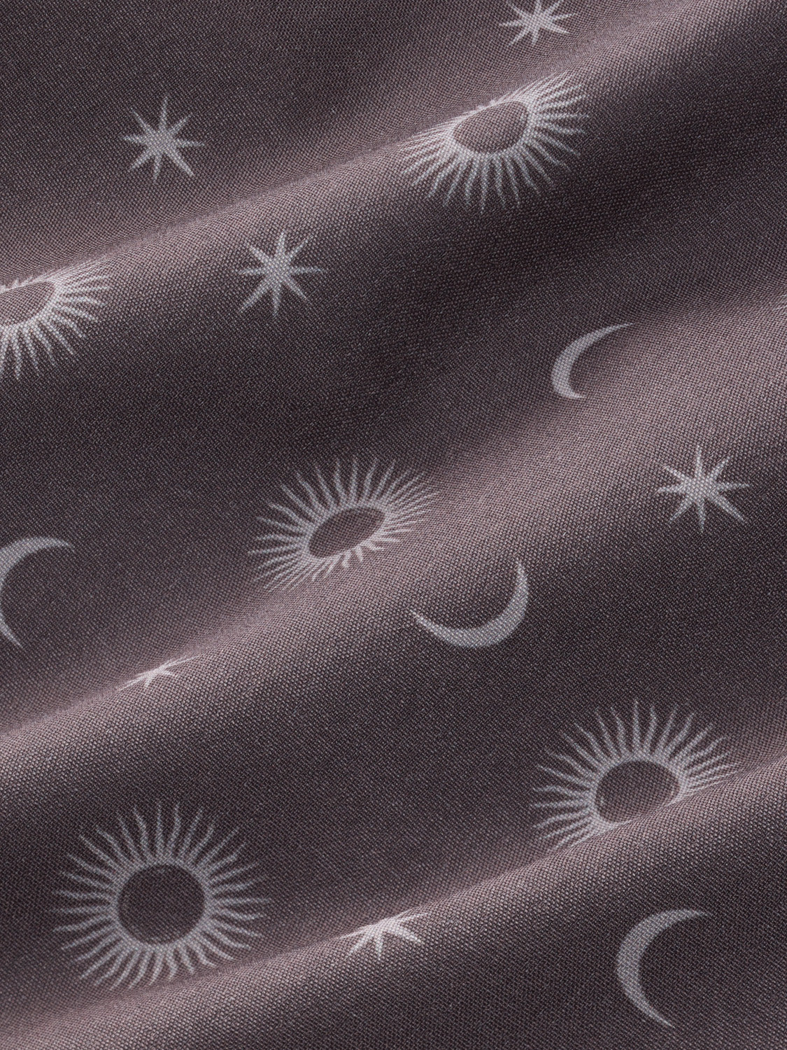 Textile with celestial pattern of suns, moons, and stars on a dark background