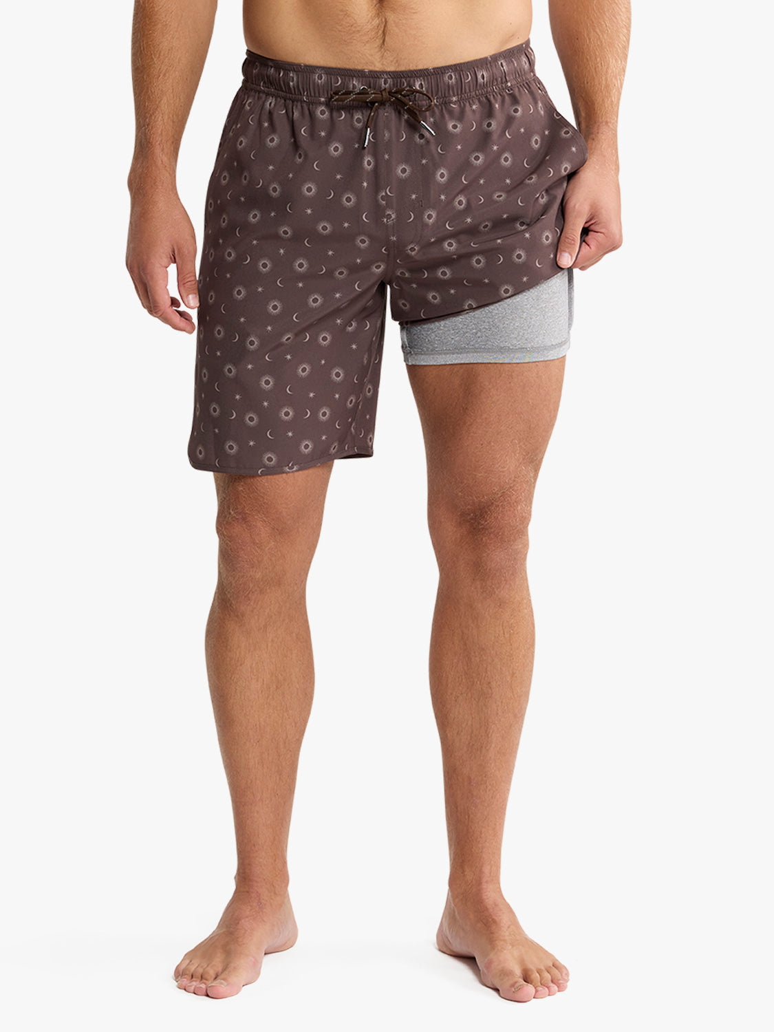 Man wearing patterned pajama shorts over gray underwear on a white background
