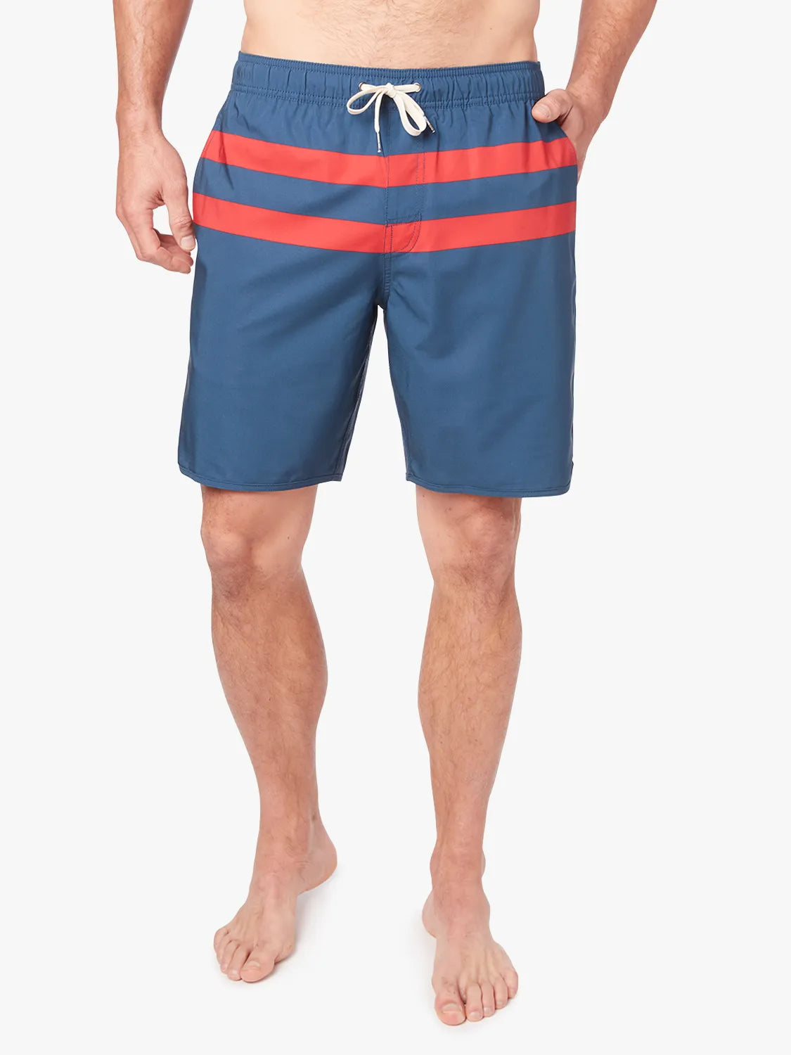 A person wearing a pair of 8 inch navy anchor trunk shorts with two red horizontal stripes and a drawstring waist with a white background. 