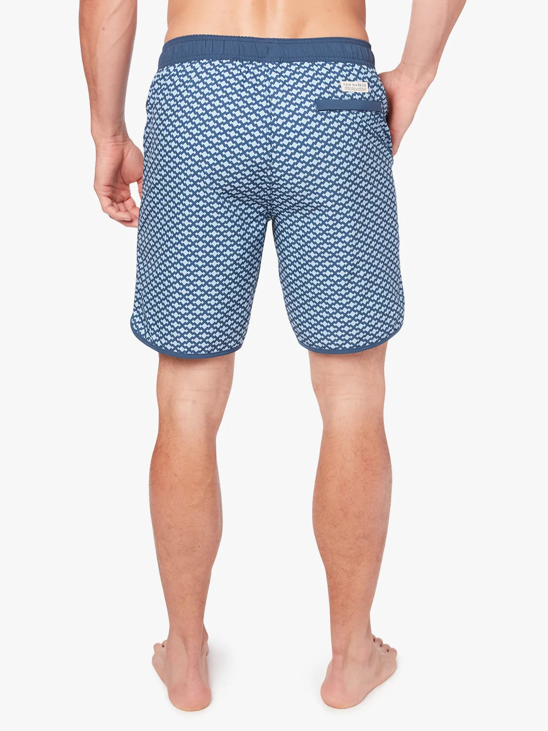 A person wearing a pair of Anchor Trunk in 8 inch inseam with a geometric pattern in shades of blue, featuring a drawstring waist showing the back view against a white background. 