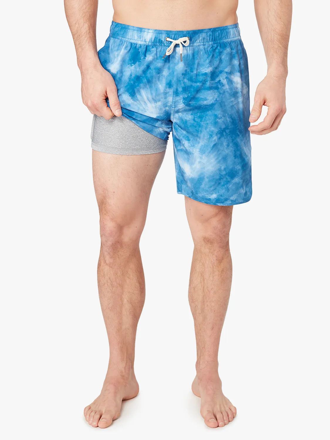 A person wearing a pair of blue tie-dye Anchor Trunk in 8 inch inseam with a drawstring waist and showing the liner. 
