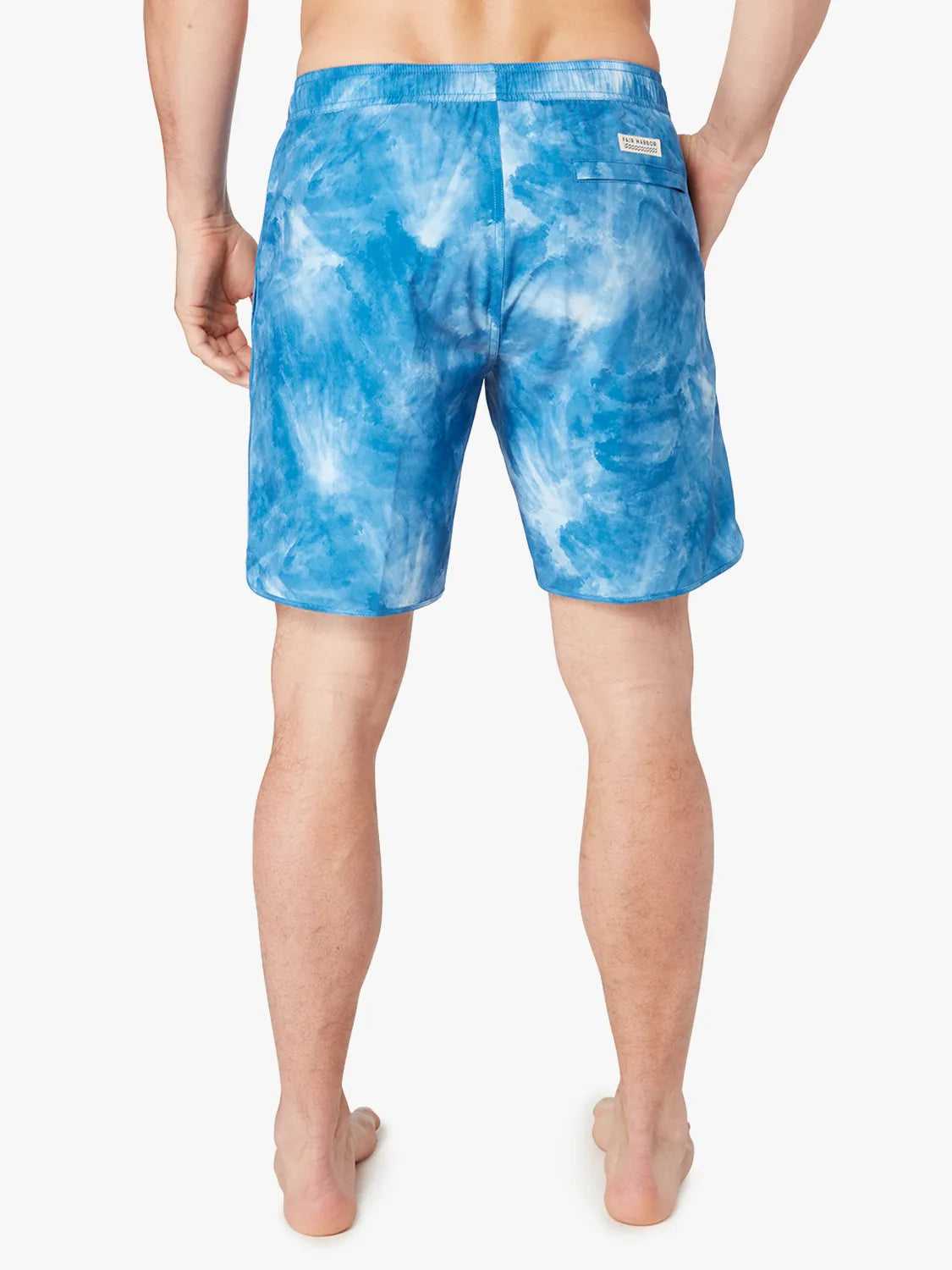 A person wearing a pair of blue tie-dye Anchor Trunk in 8 inch inseam with a drawstring waist. Showing the back view. 