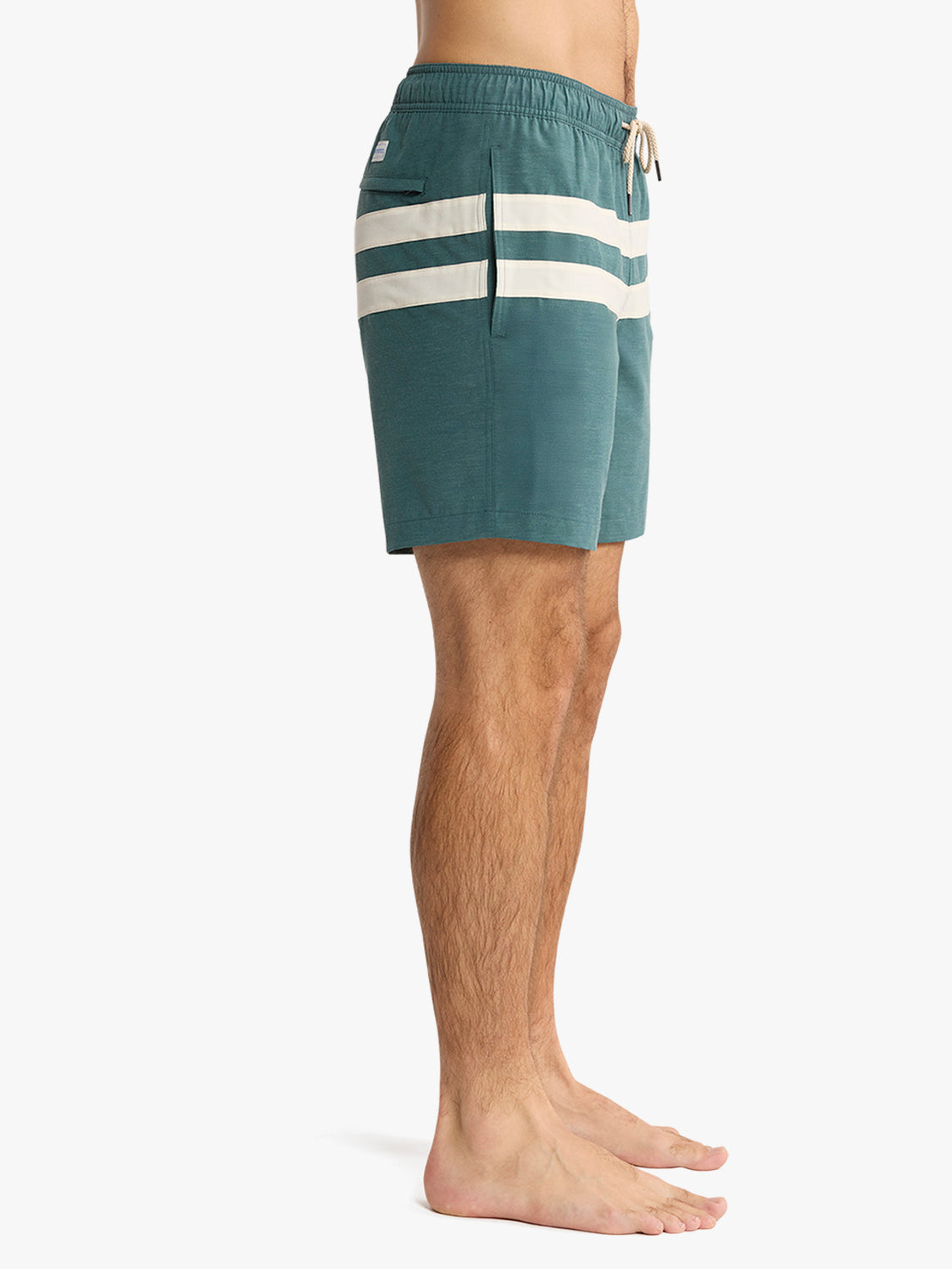 Person wearing teal swim shorts with white stripes on a white background