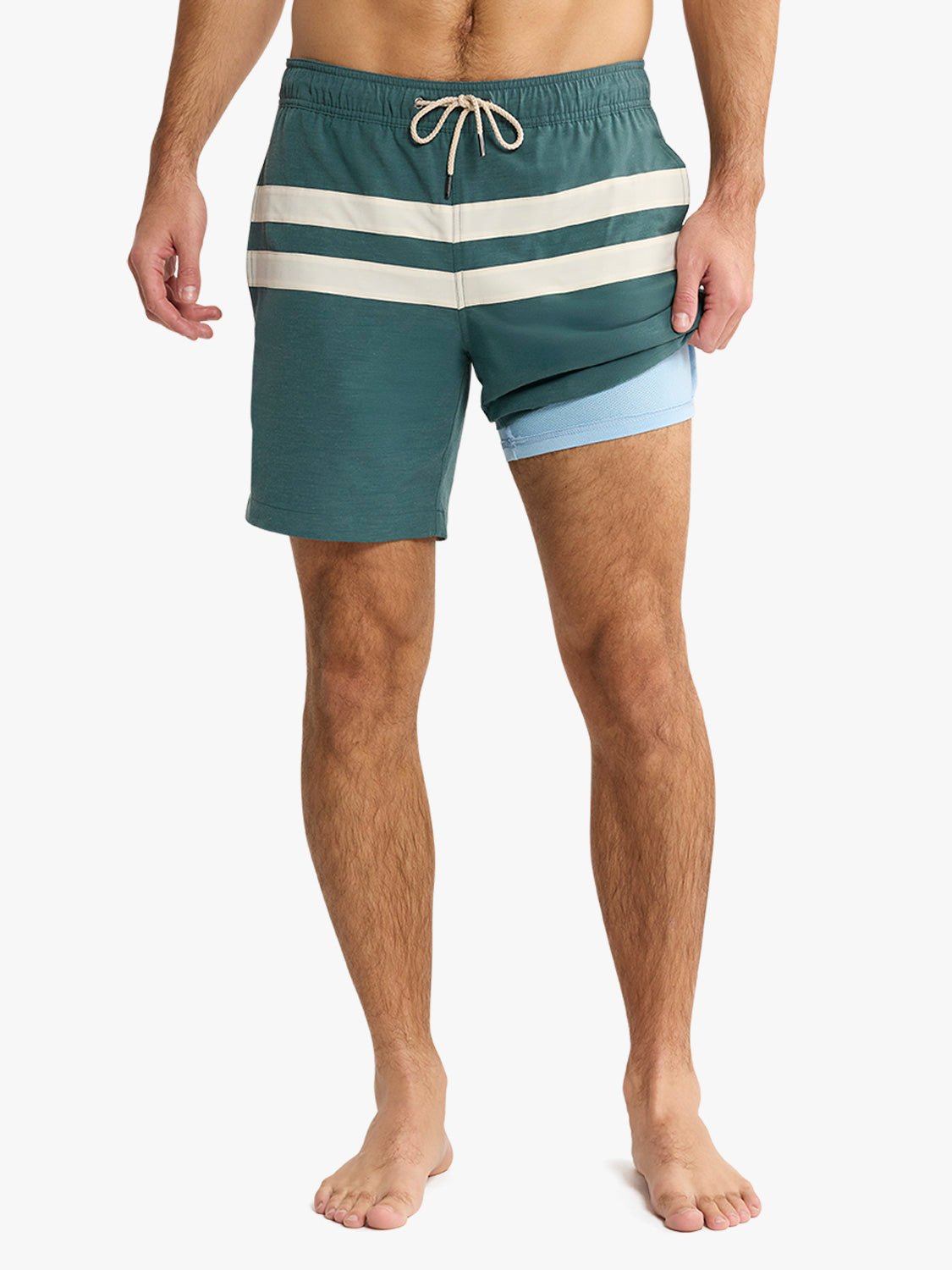 Person wearing a green and white striped swim shorts on a plain background