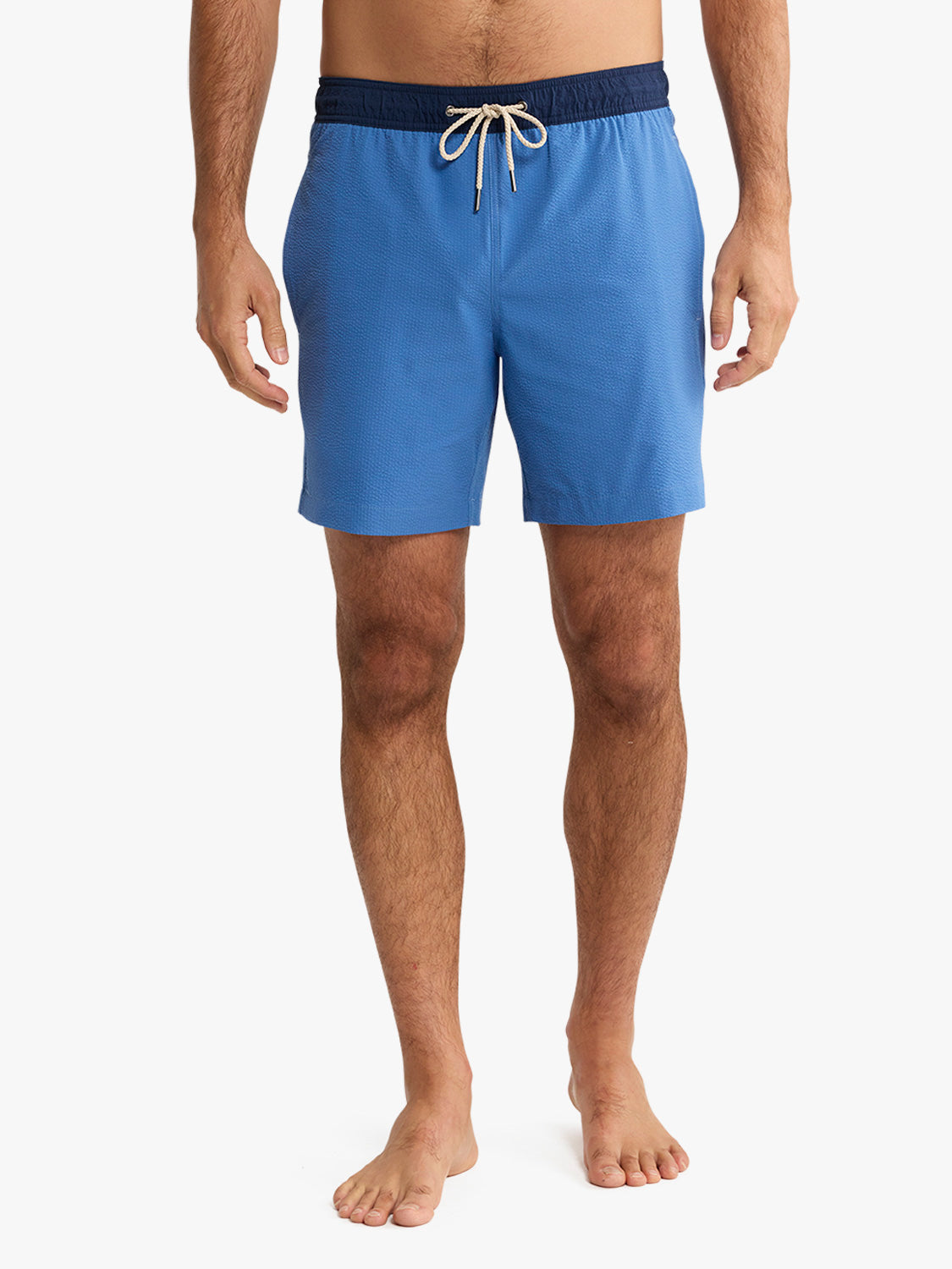 Man wearing blue swim shorts with a white background