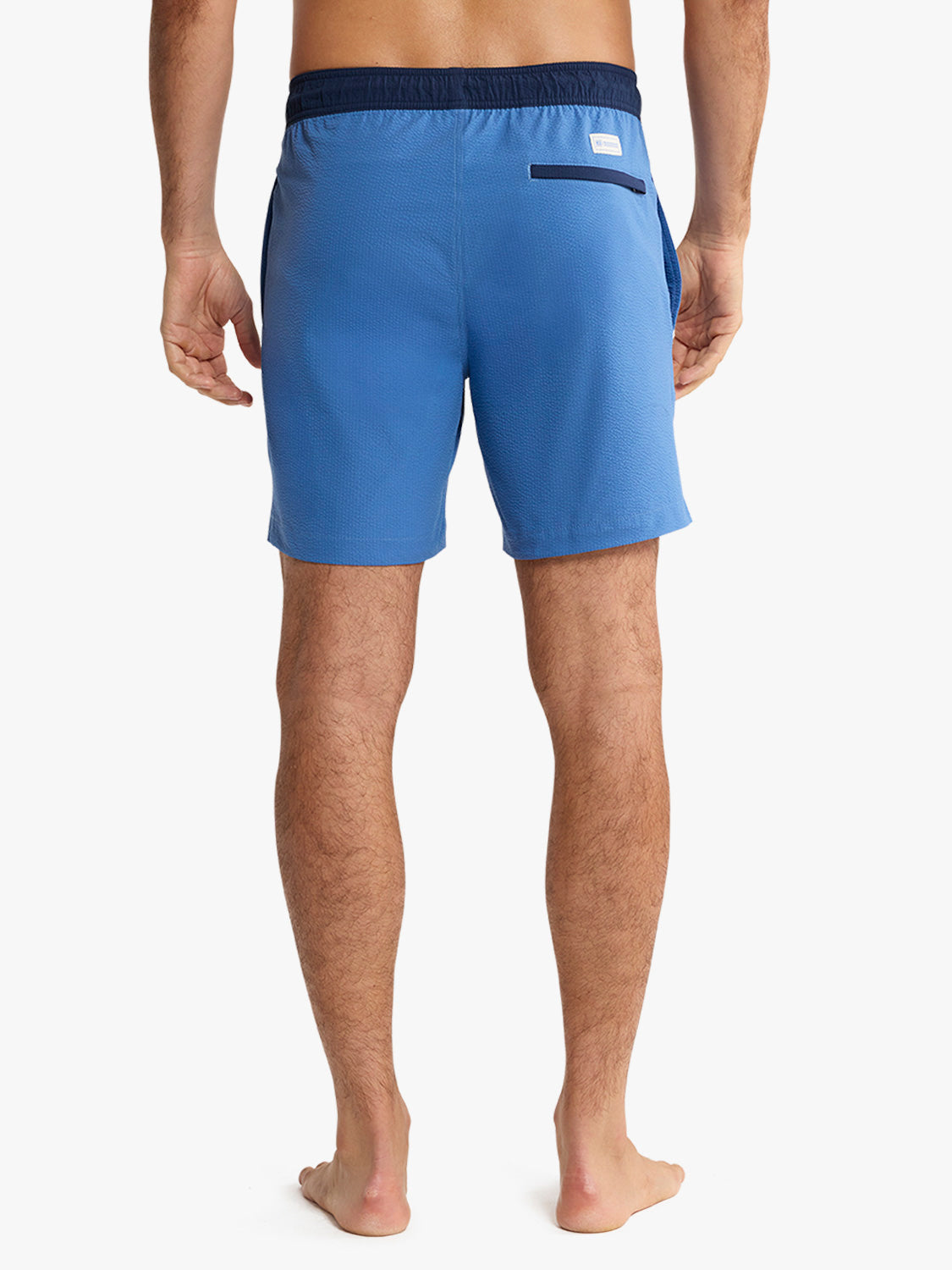 Blue swim shorts worn by a person on a white background