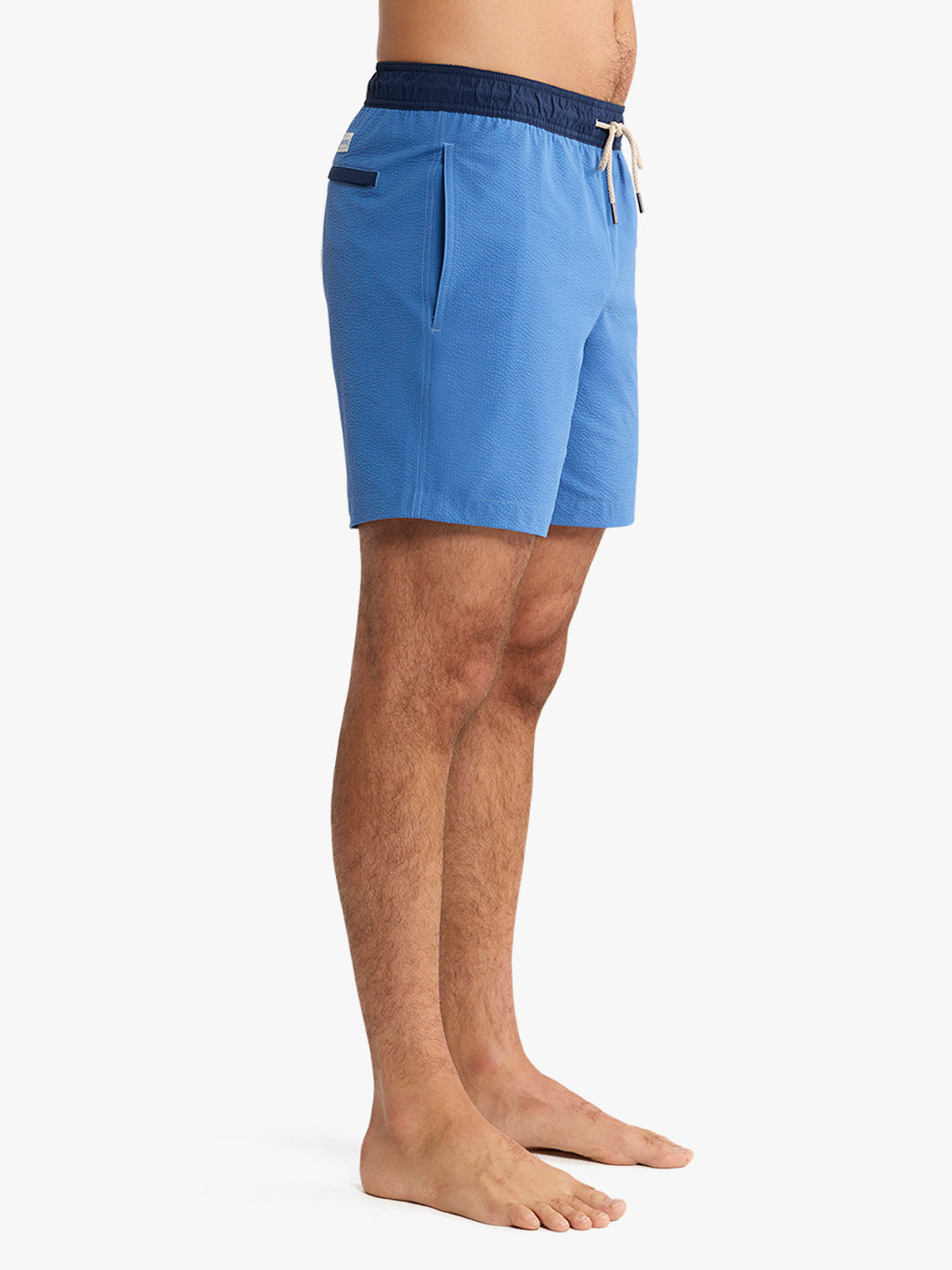 Blue swim shorts worn by a person on a white background