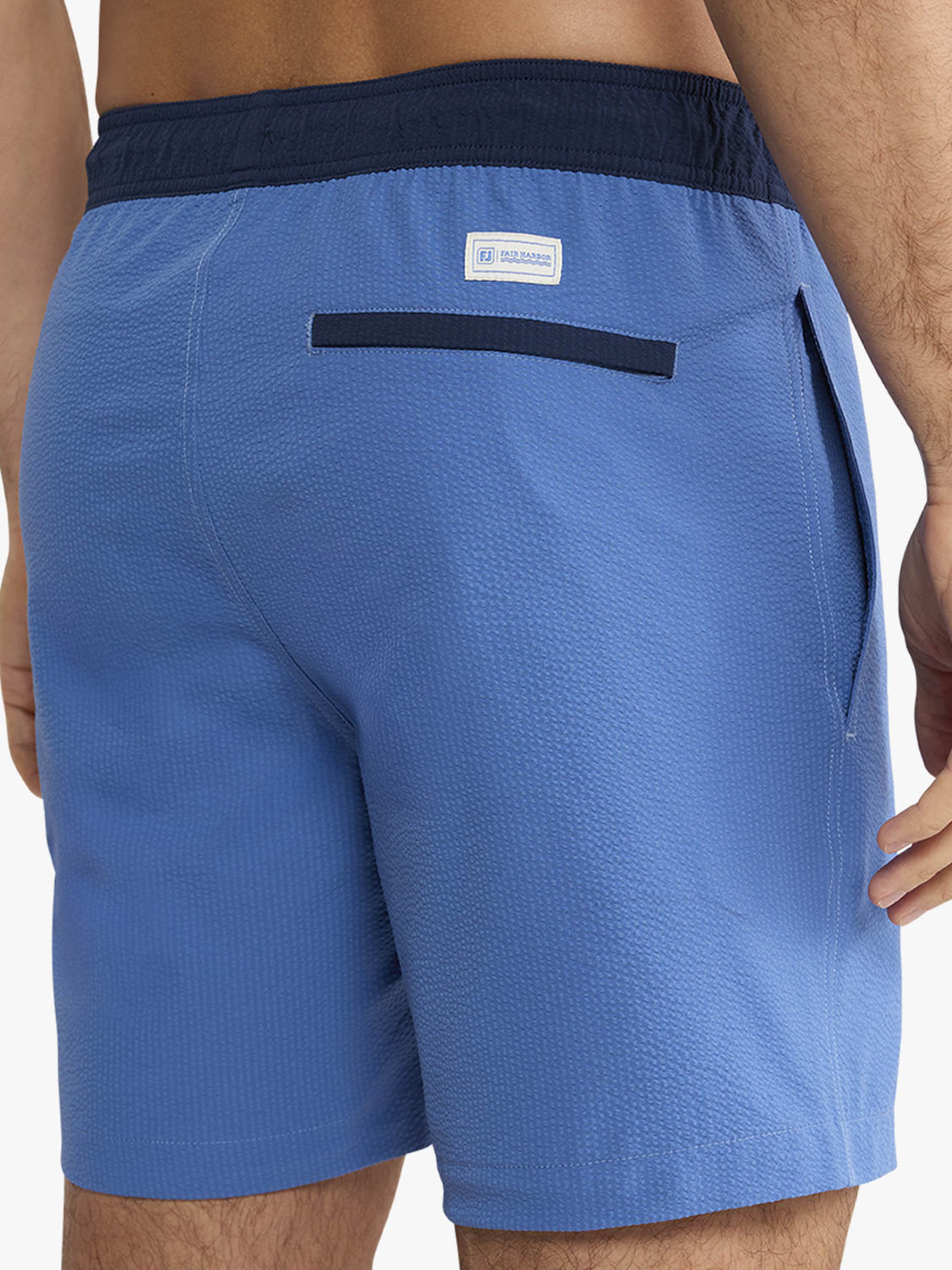 Blue swim shorts with a brand logo on the back pocket against a white background