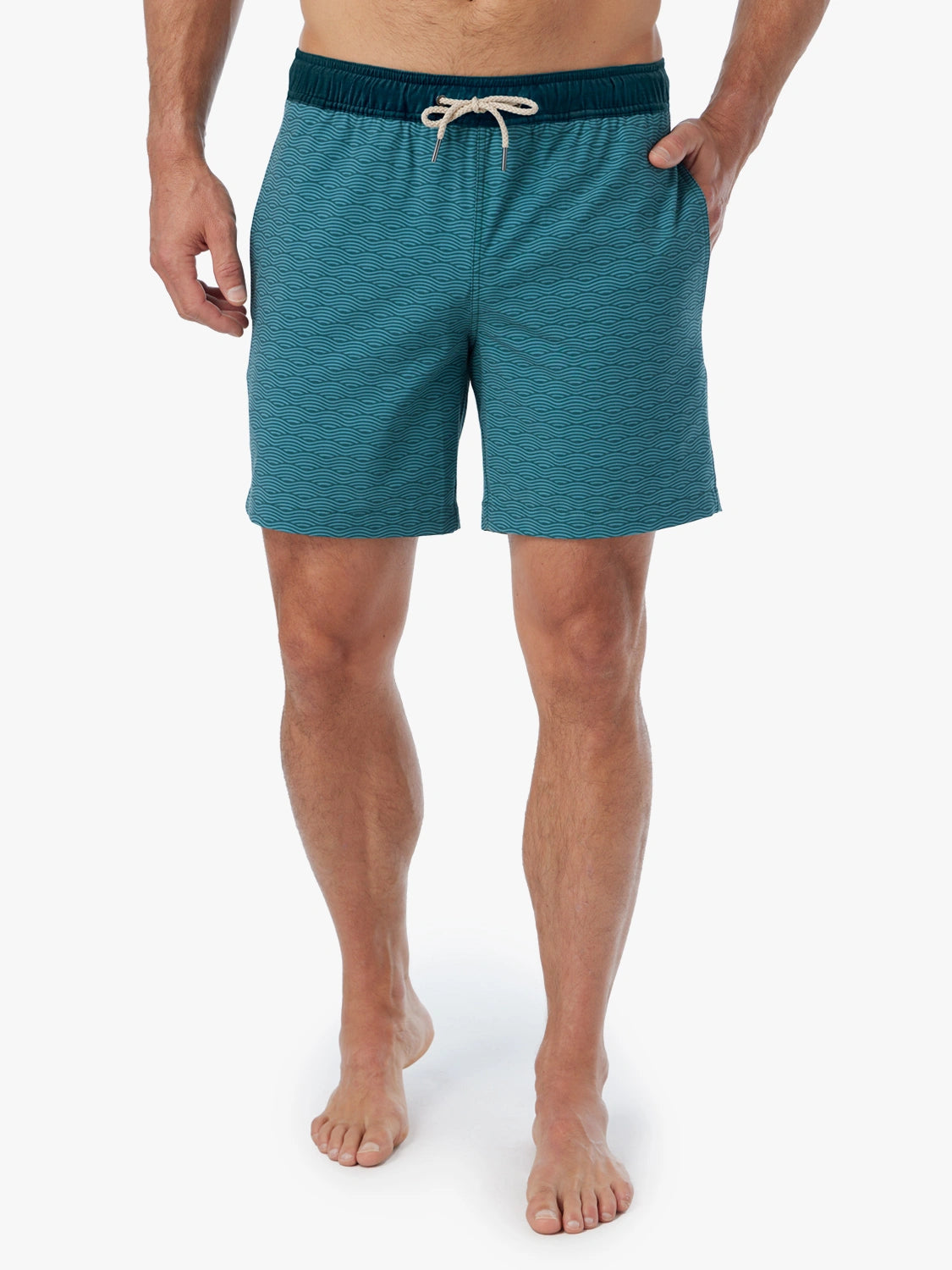 Person wearing a pair of green wave Bayberry swim trunks with a drawstring waistband.