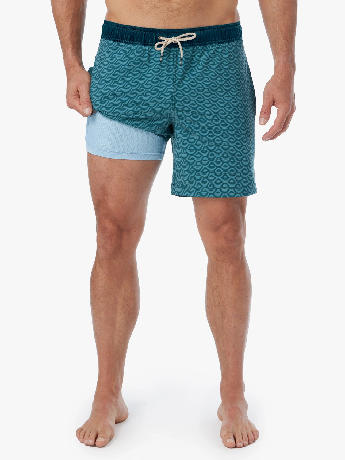 Person wearing a pair of green wave Bayberry swim trunks with a drawstring waistband, showing the lining. 